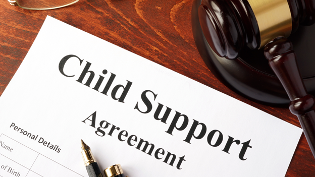 a child support agreement with a pen resting on top of it lies next to a gavel