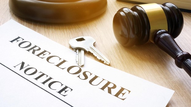 a foreclosure notice sits next to keys and a gavel on a court table