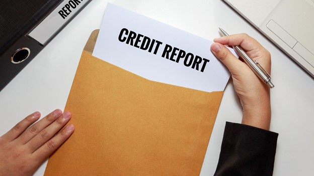 a person opens an envelope to reveal their credit report as they wonder, “how will filing Chapter 13 impact my credit?”