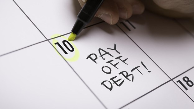 a pen circles a date on the calendar with the words “pay off debt!” written down