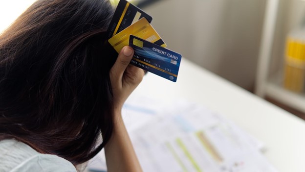 a person holds credit cards next to their head in frustration