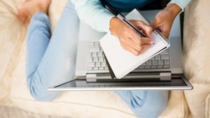 a person writes a list of common foreclosure terms you need to know in front of their laptop computer