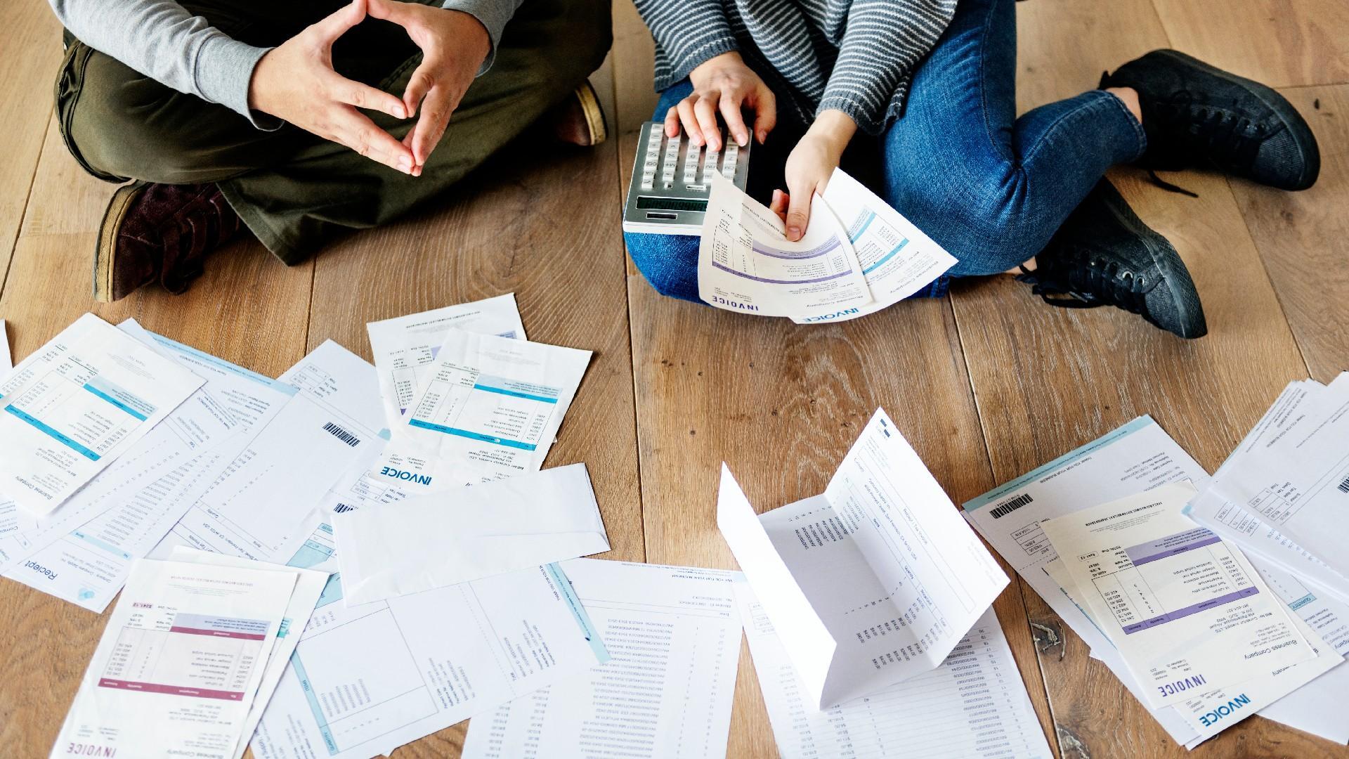 a couple manages debt while sitting on the floor with papers and a calculator and probably wondering whether lawsuits and judgements are viable options