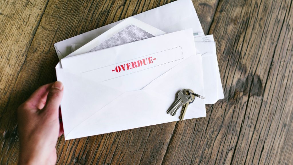 a person holds an envelope filled with overdue bills