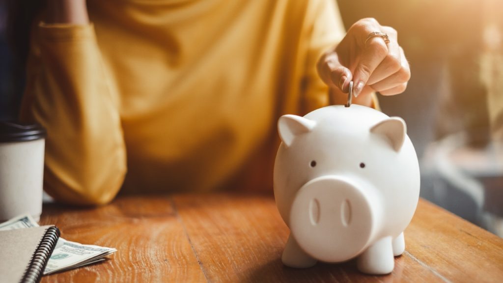 a person deposits money into a piggy bank