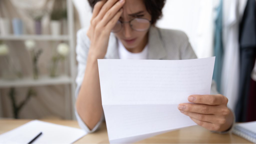 a person is stressed reading a letter as they experience one of the stages of foreclosure in Texas