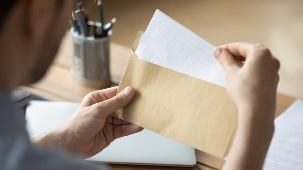 a person opens a letter from a brown envelope