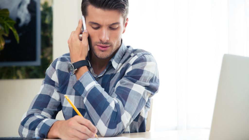 a person takes notes while speaking on the phone