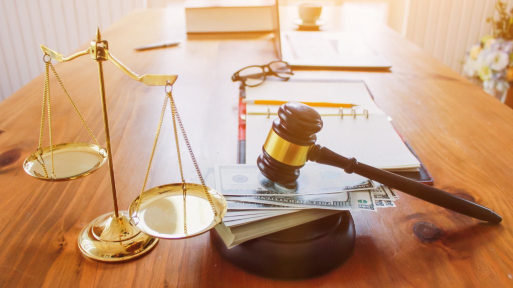 a gavel sitting on top of money sits next to justice scales because a client decided to schedule a free consultation with a Chapter 7 bankruptcy attorney