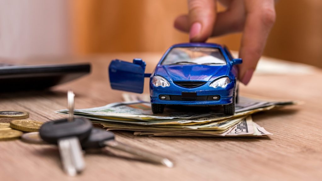 a toy car sits on top of cash and car keys