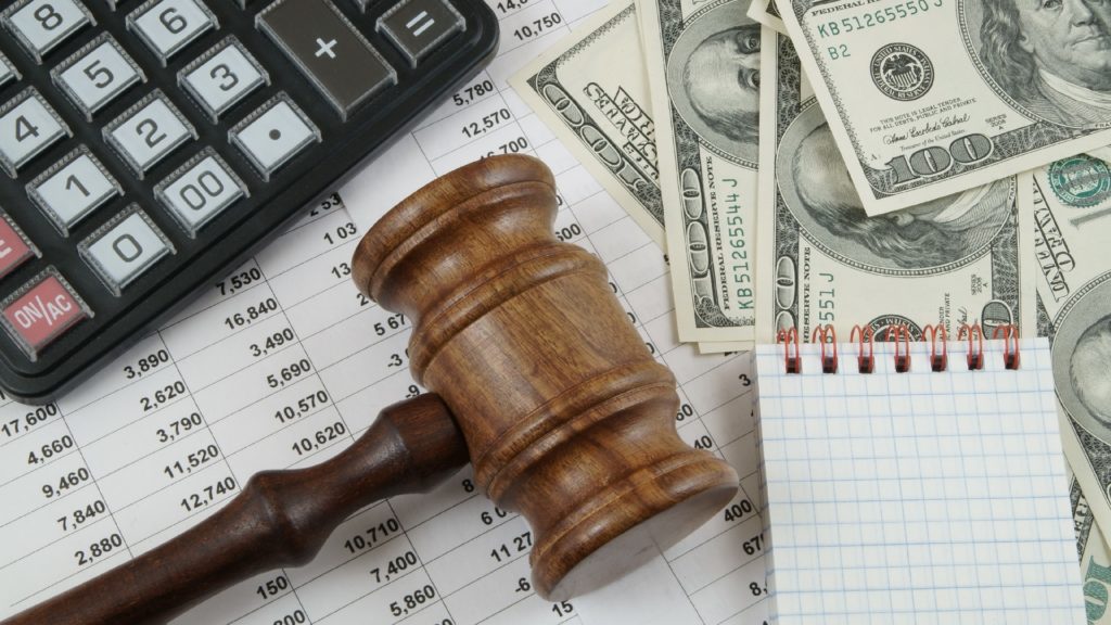 a gavel sits next to money, documents and a calculator