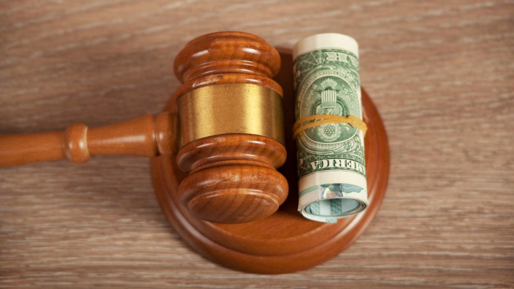 a rolled up dollar bill-and-gavel-on-wooden-table