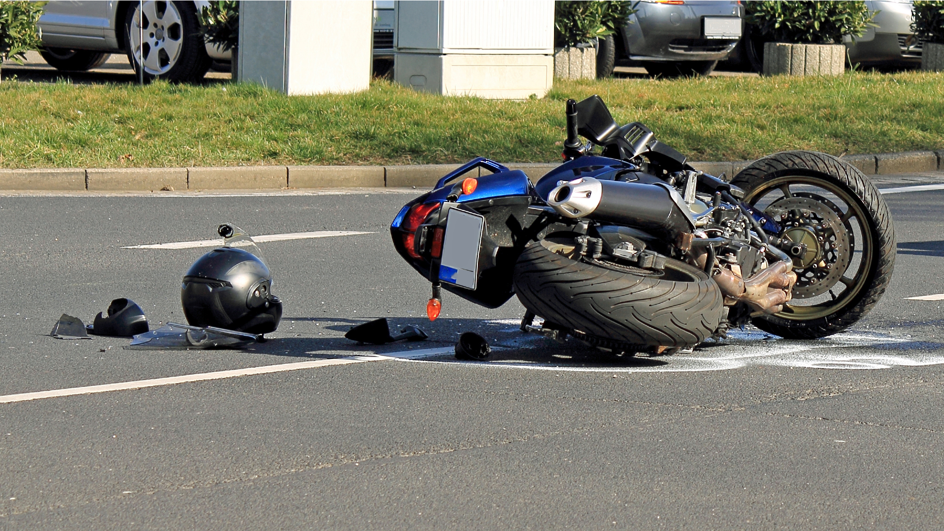 A blue motorcycle and a helmet turned over in middle of road