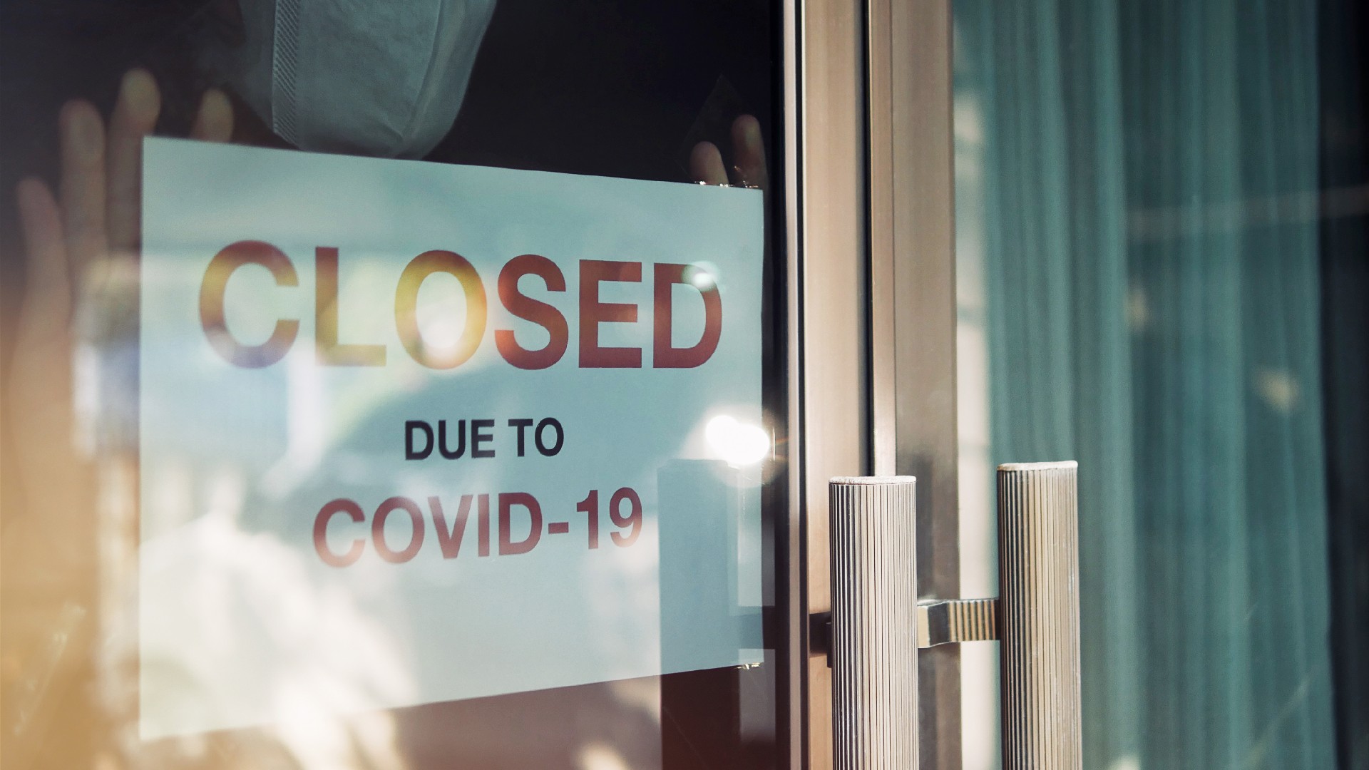 A sign on a business door says, “Closed due to COVID-19”