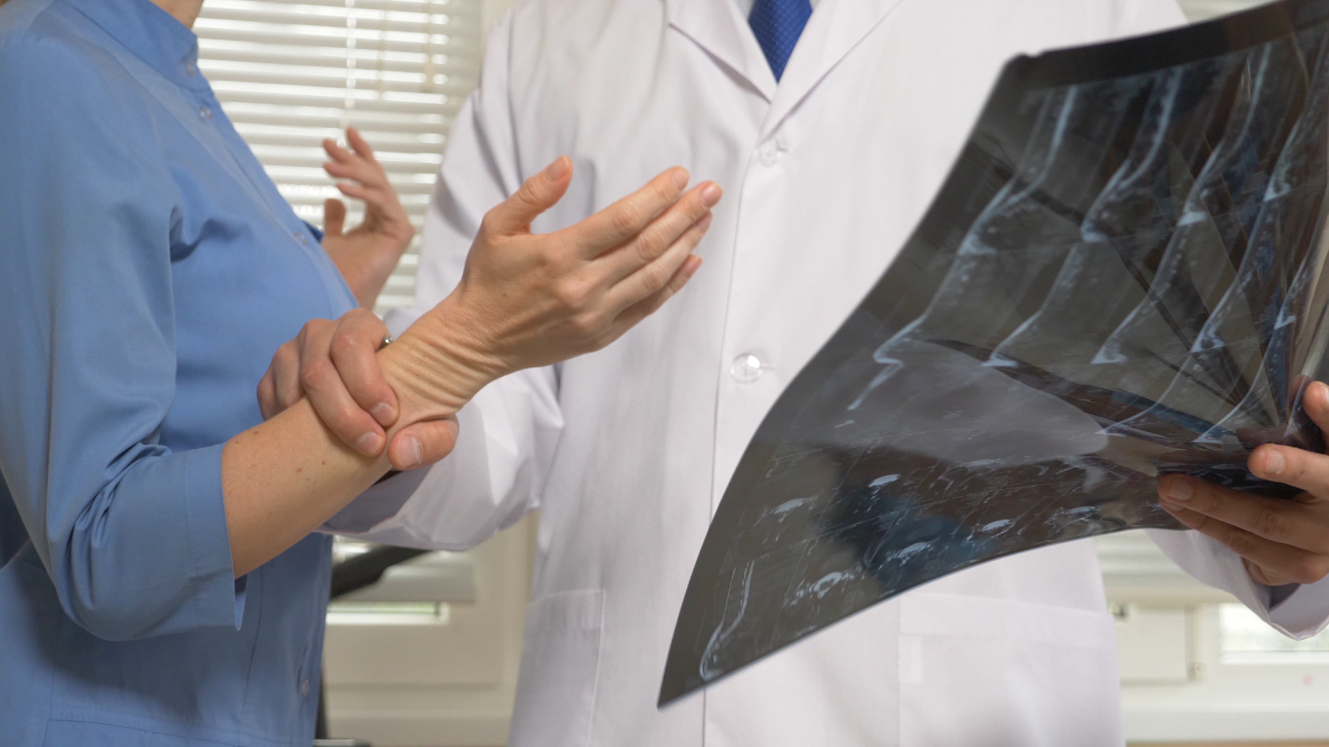 A doctor holding an x-ray while gripping their patient’s wrist