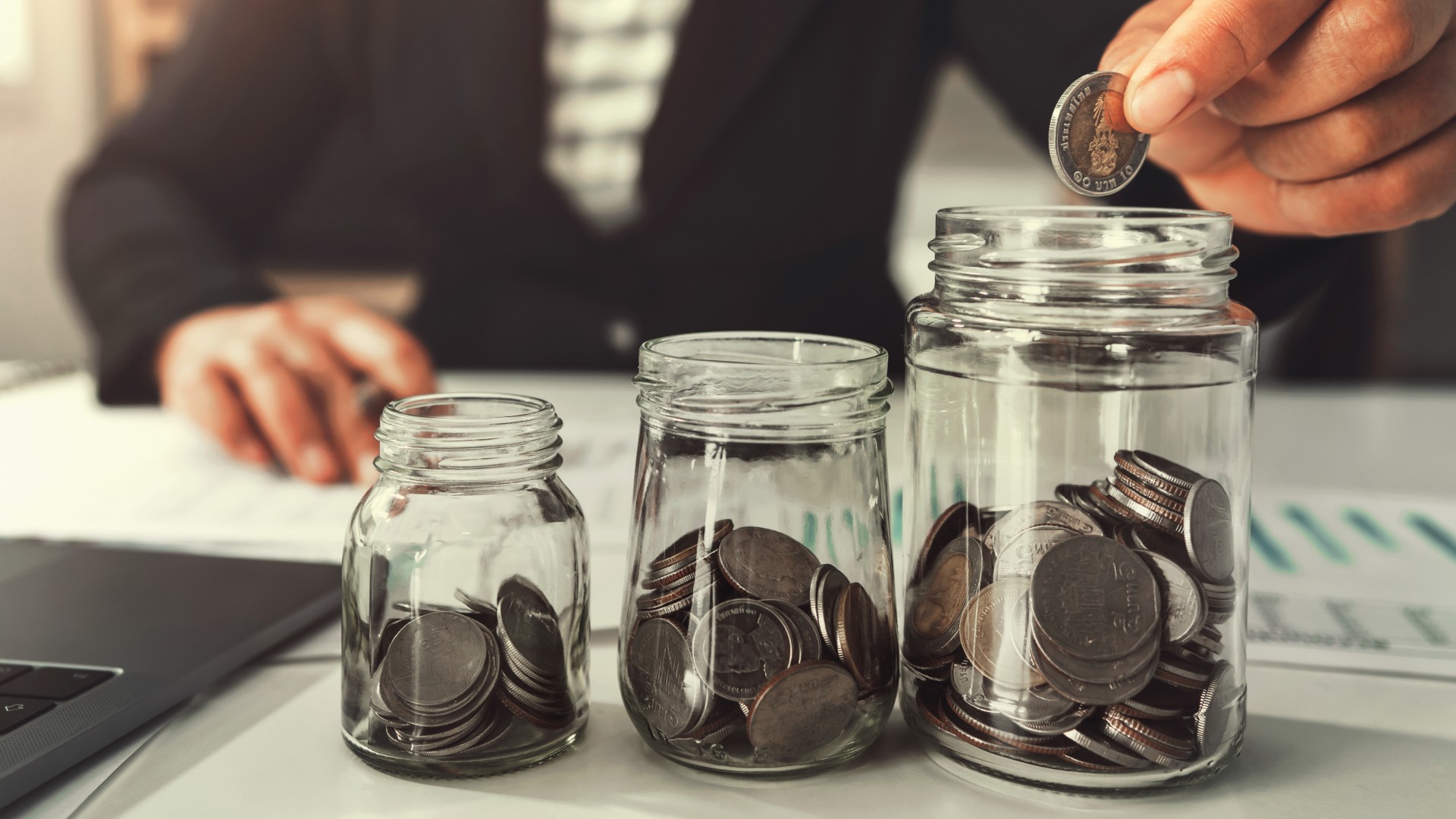 A hand puts coins in a jar