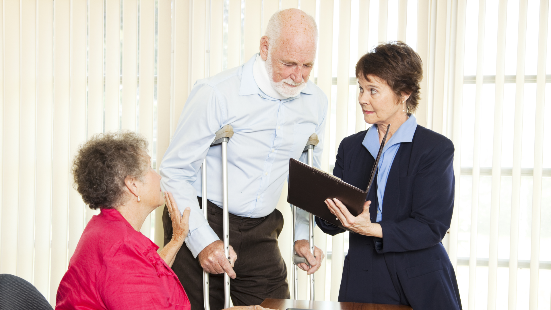 A man walks on crutches and wears neck brace speaks to personal injury lawyer while his partner helps guide him