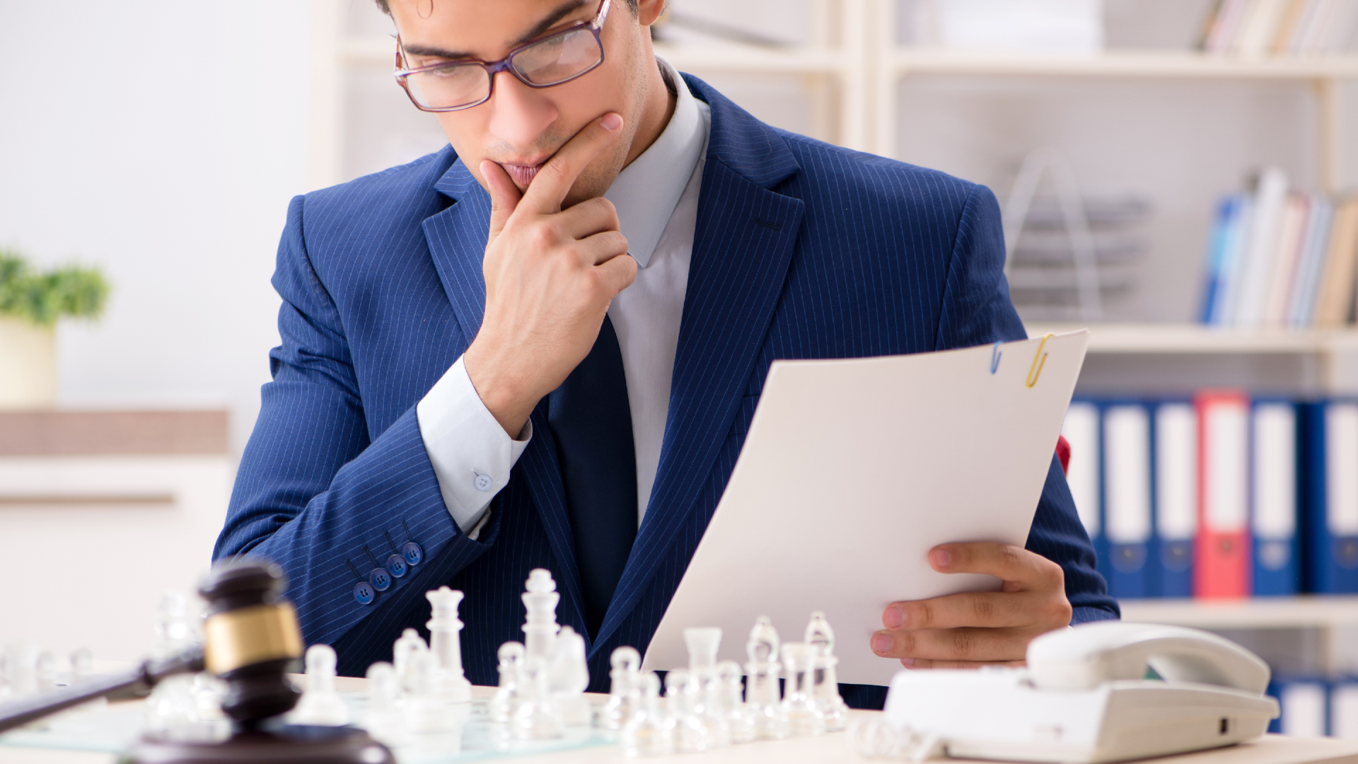 A lawyer looking at chess set with paperwork in hand
