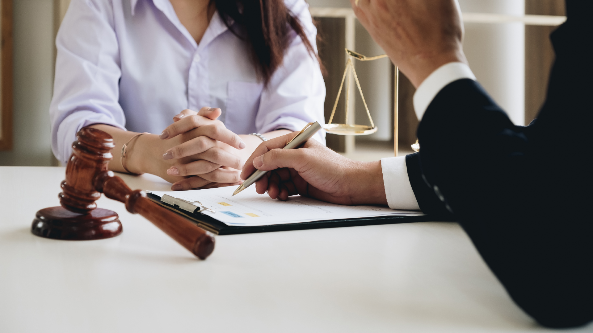 A lawyer reviewing paperwork with their client with a gavel off to the side