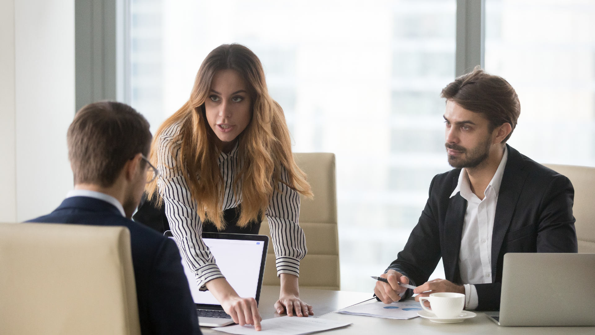 A lawyer points at paperwork in front of client as their colleague looks onward