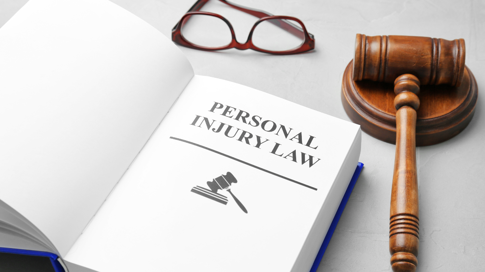 A personal injury law book sitting next to a gavel and a pair of glasses