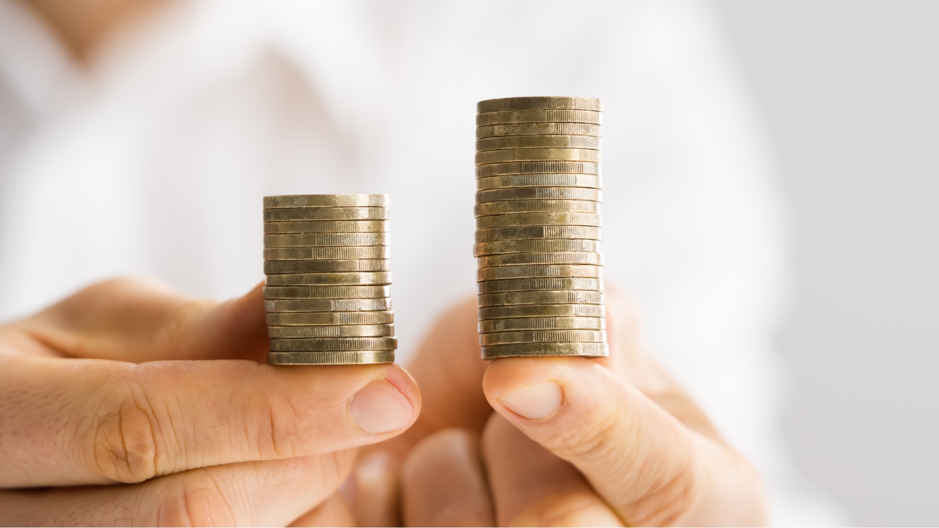 A person’s hand holds two piles of coins