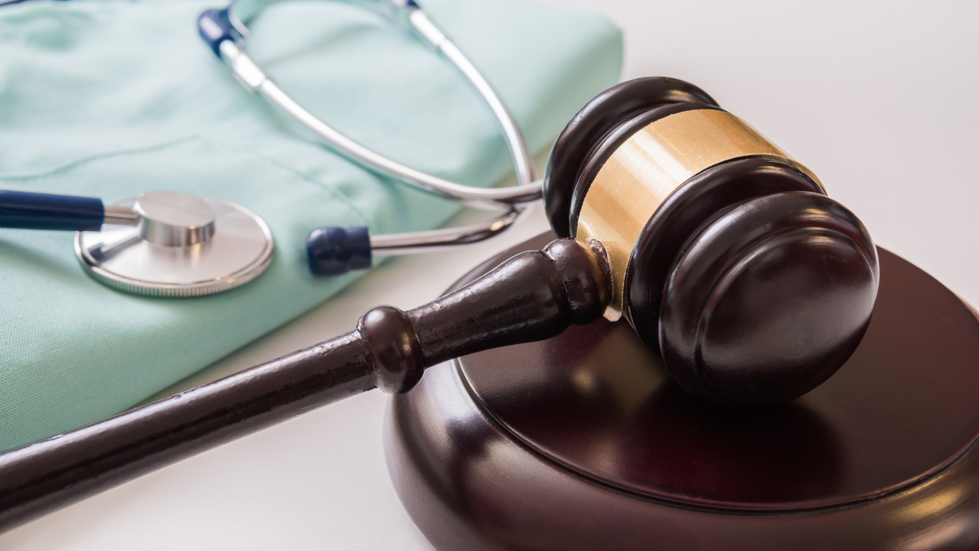 A stethoscope and a gavel sitting next to a doctor’s scrubs