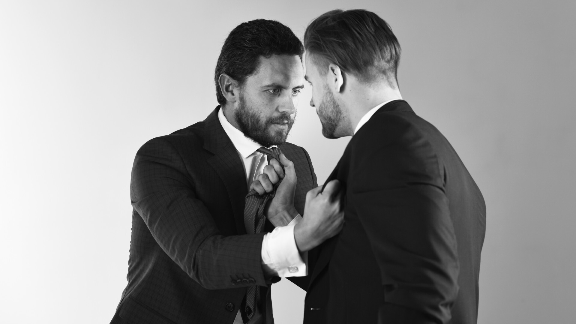 Two men glaring at each other as they hold each other’s ties