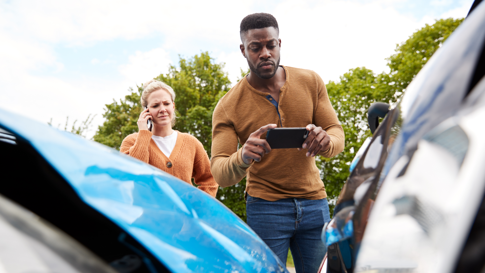 Two people taking a photo of a car accident scene