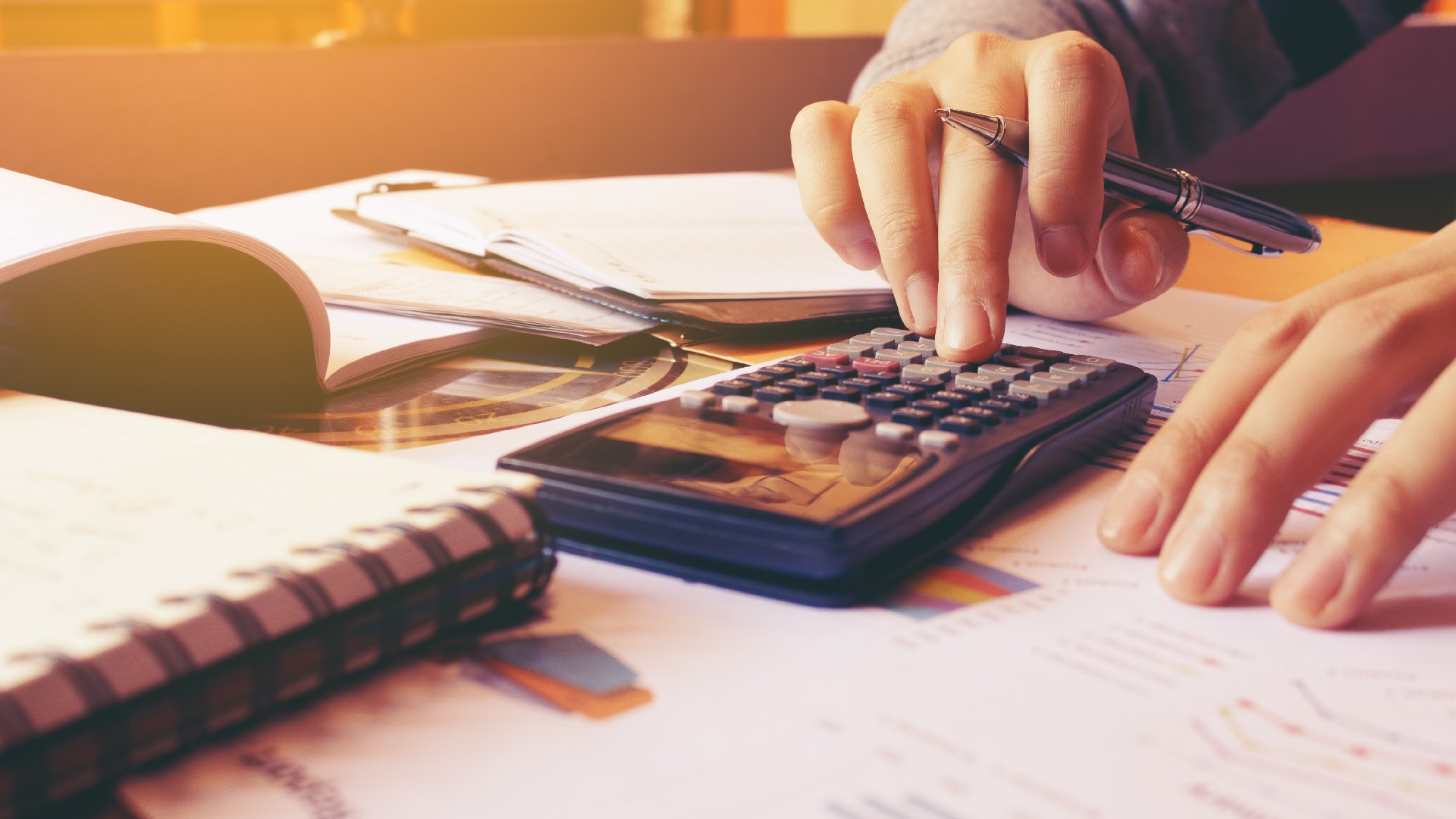 A credit counselor types on a calculator at their desk