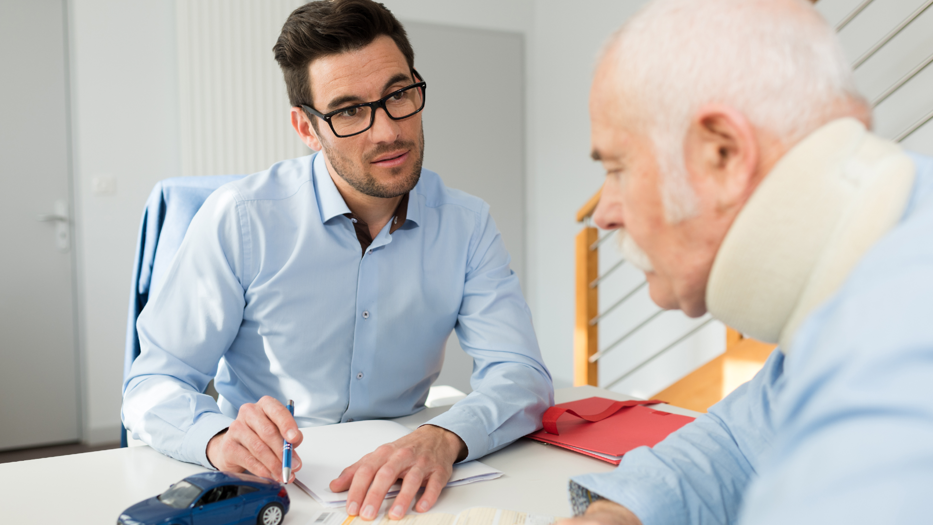 A younger man speaks to an older man who is wearing neck brace