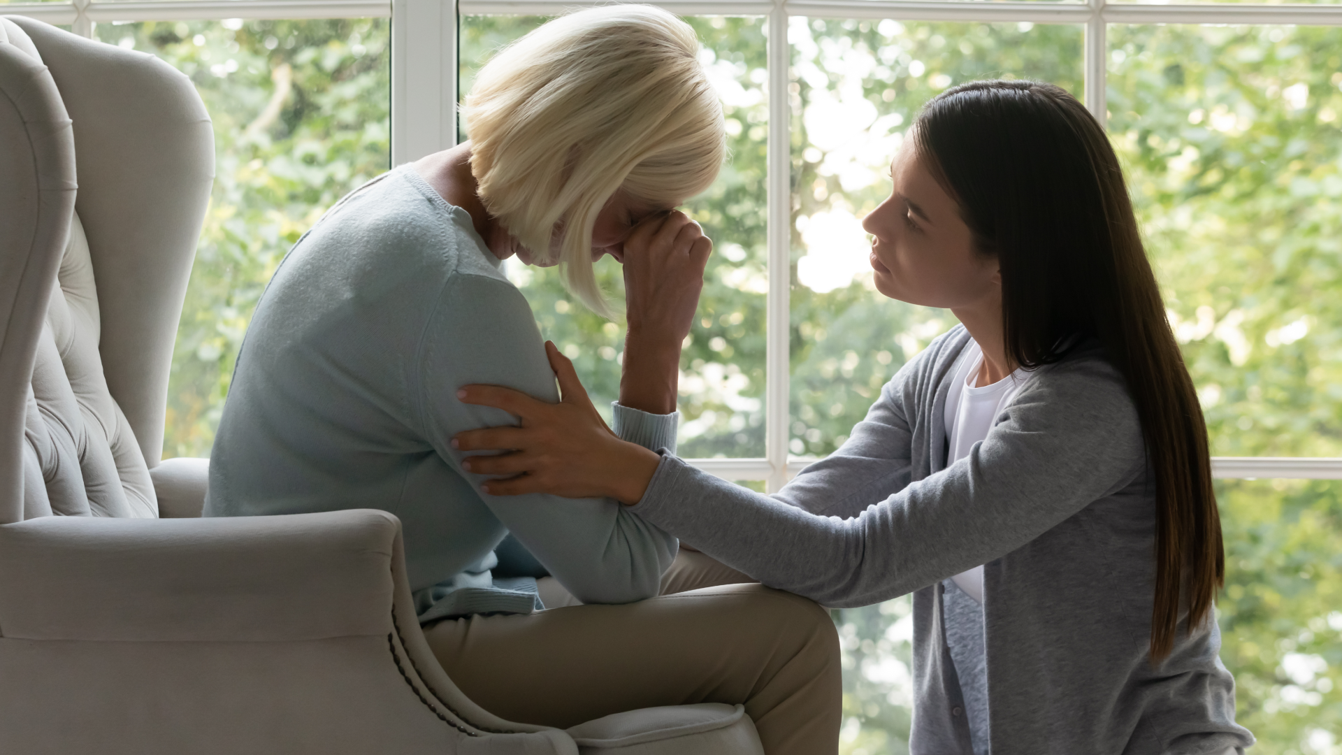 A younger woman consoling an older woman on a chair