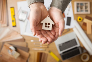 Hands holding a little wooden home