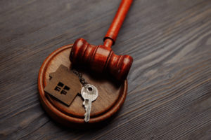 Foreclosure Lawyer Texas - Judge gavel and key chain in shape of two splitted part of house on wooden background. Concept of real estate auction or dividing house when divorce, division of property, real estate, law system